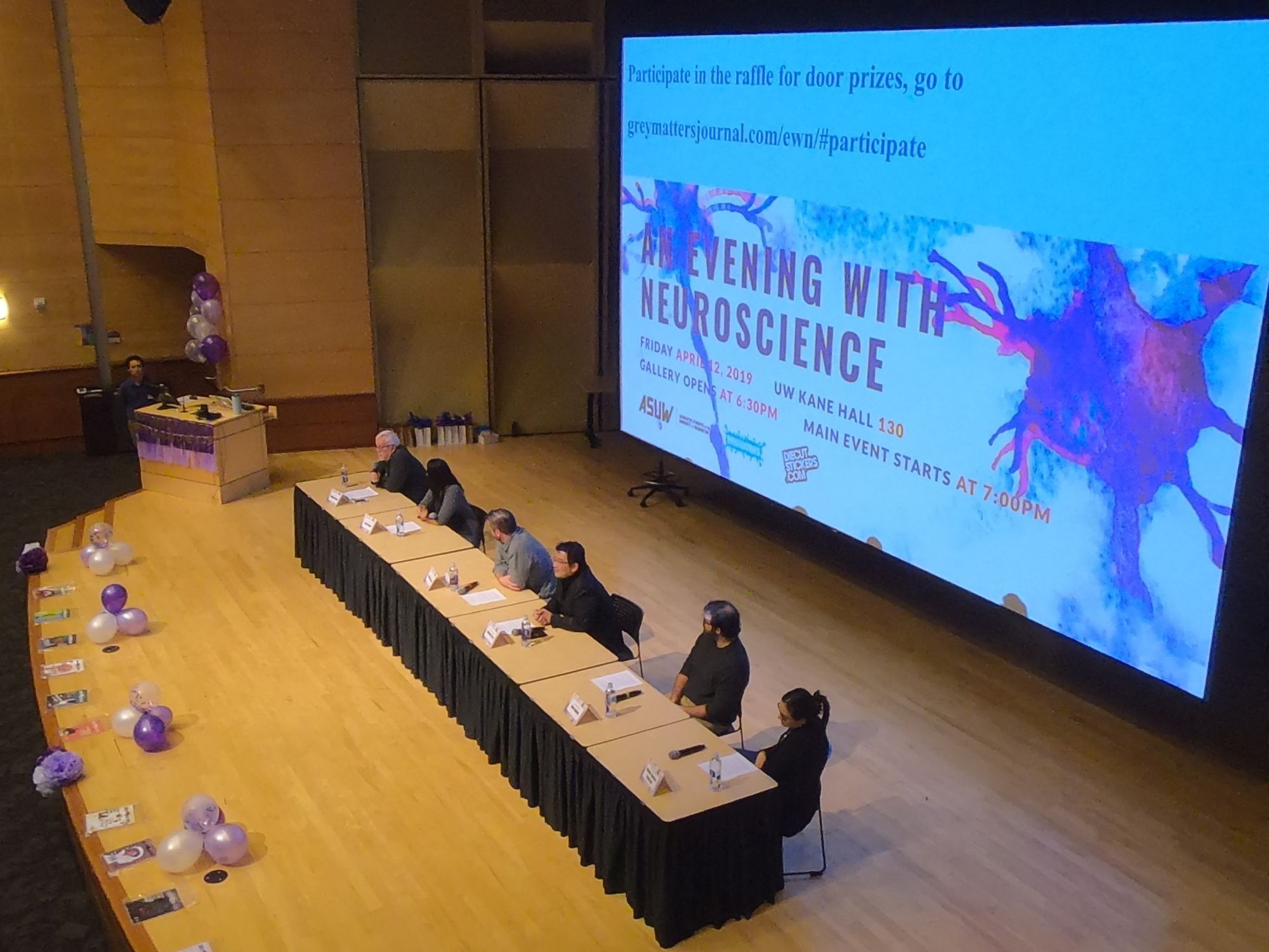 The top left image features the EWN panelists on the light brown wooden stage of the Kane Hall auditorium at the University of Washington, decorated with purple and white balloons and streamers, with a title slide in the background displaying 'An Evening with Neuroscience' and purple and blue neurons.